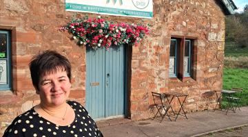 Photo of owner, Jackie, standing outside the Abbey Mill Coffee Shop.